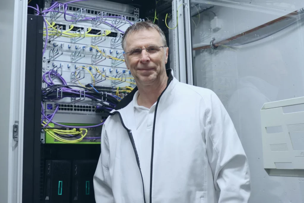 Thomas Spreitzer von TSE Services steht vor einem offenen Serverschrank.